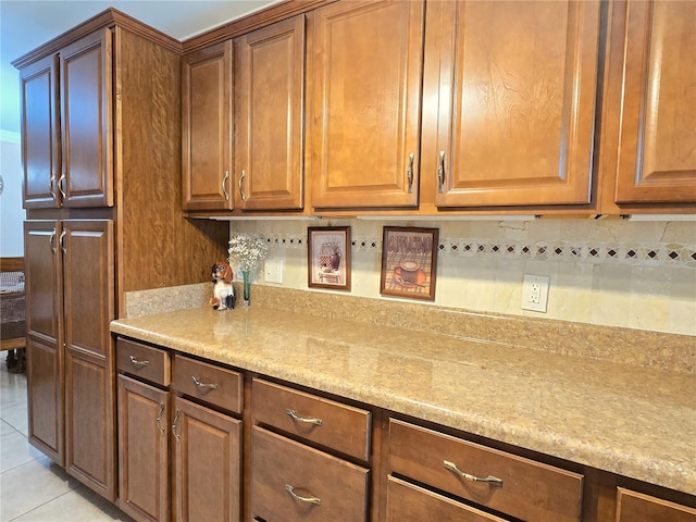 kitchen featuring light tile patterned floors, decorative backsplash, and brown cabinets