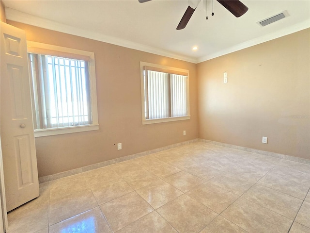 empty room featuring tile patterned floors, visible vents, baseboards, and ornamental molding