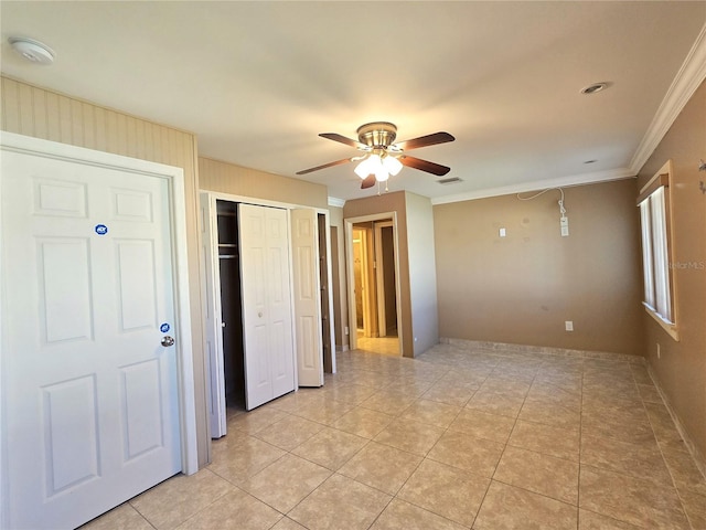 interior space with light tile patterned floors, visible vents, crown molding, and ceiling fan