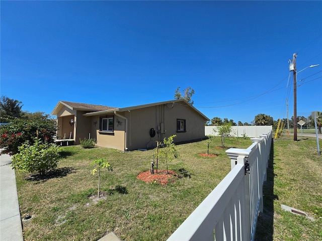 view of property exterior with stucco siding, fence private yard, and a yard