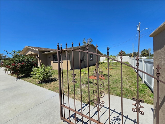 view of front of property with a gate, stucco siding, a front yard, and fence