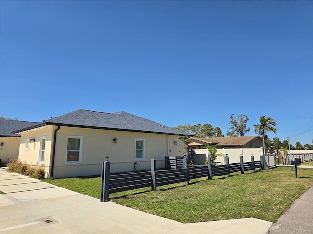 view of front of property featuring a front lawn, roof with shingles, a fenced front yard, and stucco siding