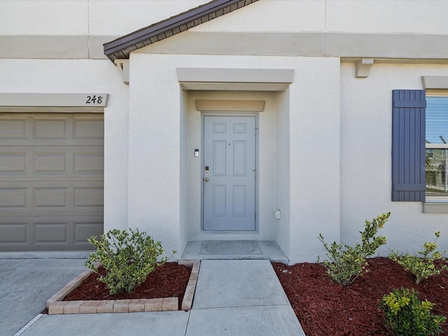 entrance to property with stucco siding and a garage