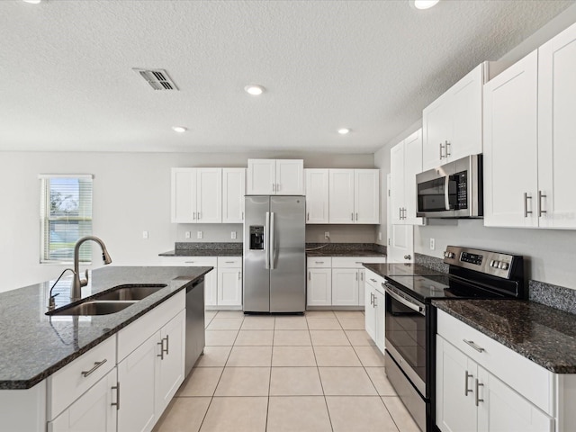 kitchen with light tile patterned floors, white cabinets, appliances with stainless steel finishes, and a sink