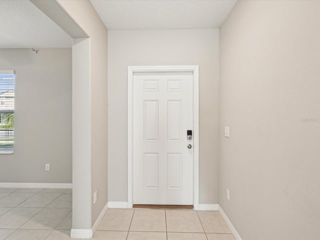 interior space with light tile patterned floors, a textured ceiling, and baseboards