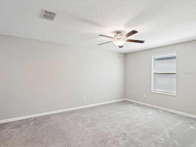 empty room with visible vents, carpet floors, baseboards, and ceiling fan