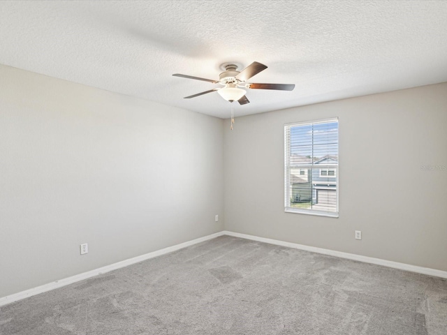 carpeted spare room featuring baseboards, a textured ceiling, and a ceiling fan