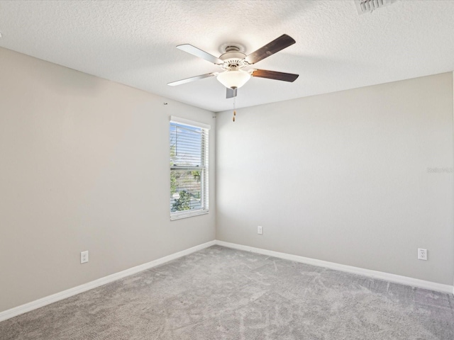 empty room with visible vents, a textured ceiling, carpet, baseboards, and ceiling fan