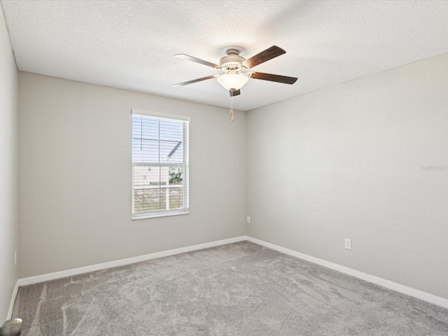 carpeted spare room featuring a textured ceiling, baseboards, and ceiling fan