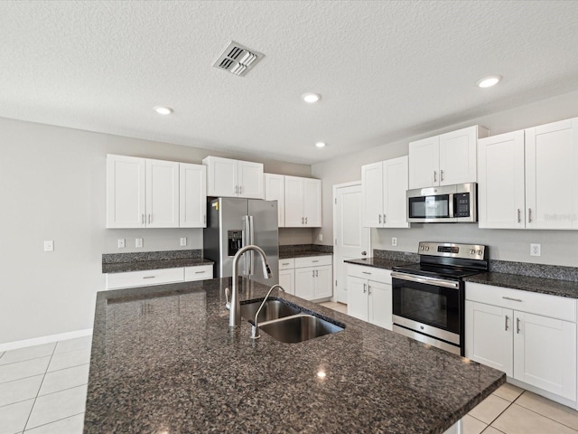 kitchen with visible vents, a center island with sink, a sink, appliances with stainless steel finishes, and light tile patterned flooring