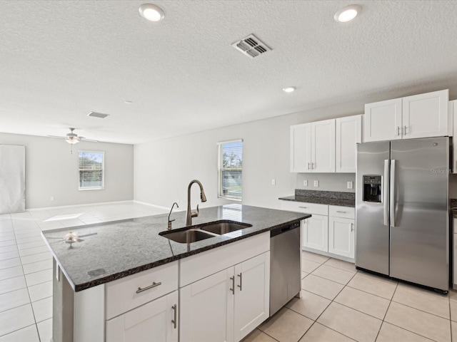 kitchen featuring visible vents, a sink, dark stone countertops, stainless steel appliances, and light tile patterned flooring