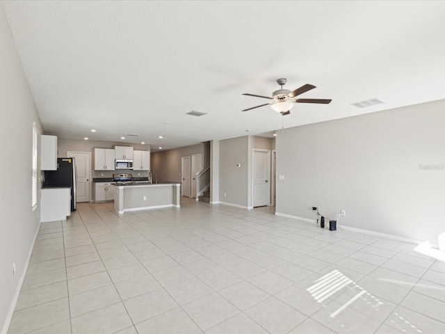 unfurnished living room featuring light tile patterned floors, visible vents, baseboards, and ceiling fan