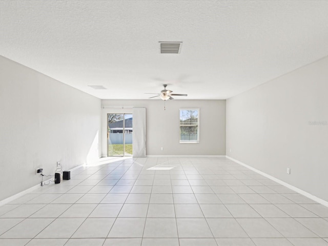 empty room featuring light tile patterned floors, baseboards, visible vents, ceiling fan, and a textured ceiling