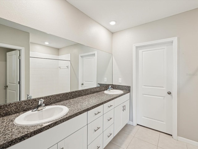 bathroom with tile patterned floors, double vanity, tiled shower, and a sink