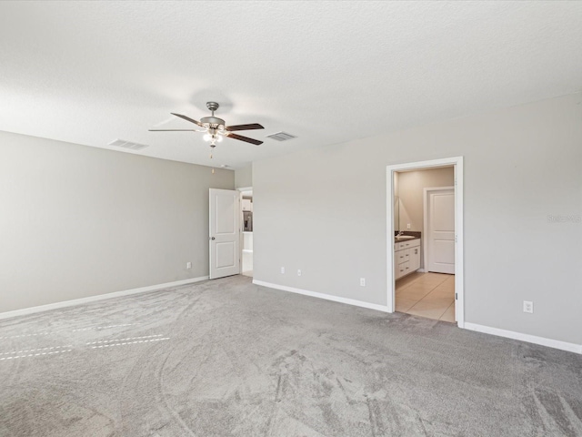 unfurnished bedroom with visible vents, baseboards, light colored carpet, and a textured ceiling