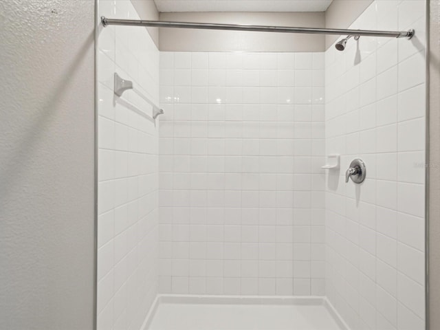 bathroom featuring a shower stall and a textured wall