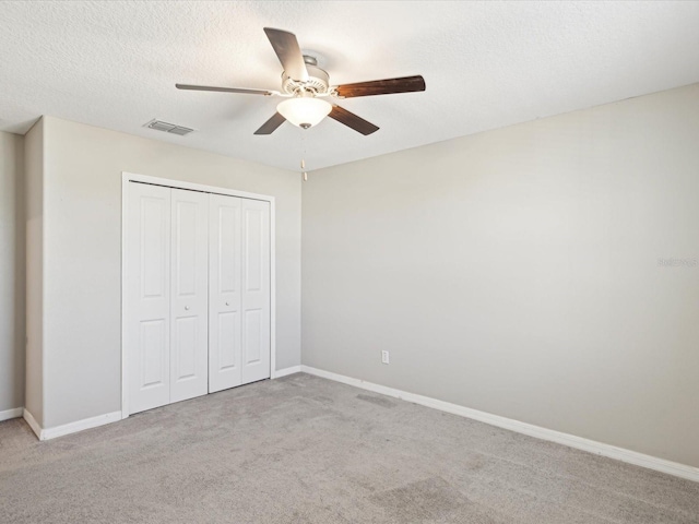 unfurnished bedroom featuring a closet, visible vents, a textured ceiling, and carpet