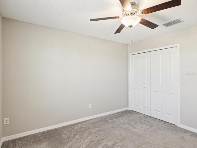 unfurnished bedroom featuring visible vents, ceiling fan, baseboards, carpet, and a closet