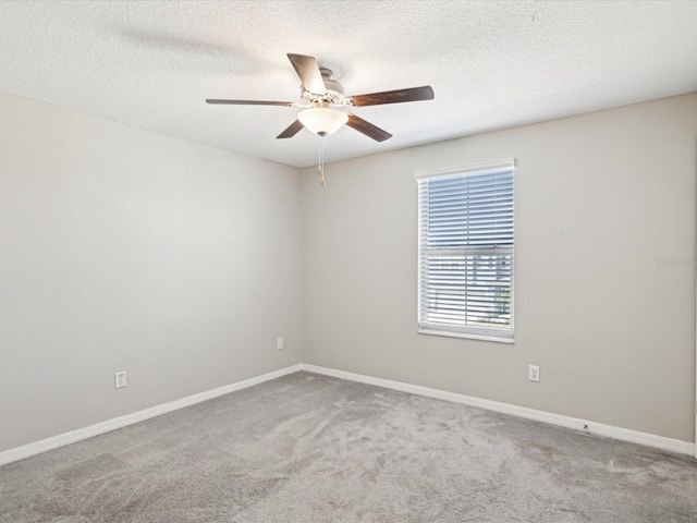 carpeted empty room with baseboards, a textured ceiling, and a ceiling fan