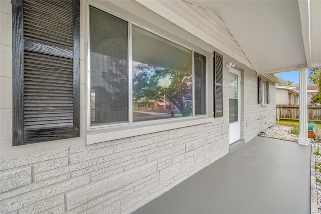 view of side of home with a patio, fence, and brick siding