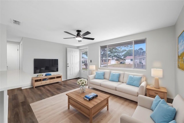 living room featuring baseboards, wood finished floors, visible vents, and ceiling fan