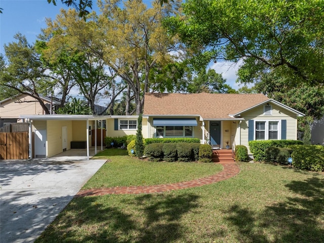 ranch-style house featuring a carport, concrete driveway, a front lawn, and fence