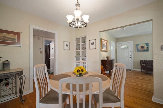 dining room with baseboards, an inviting chandelier, and wood finished floors