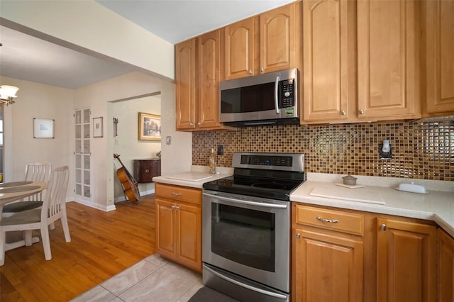 kitchen featuring decorative backsplash, appliances with stainless steel finishes, and light countertops