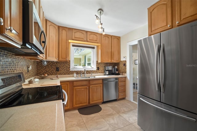 kitchen featuring tasteful backsplash, light countertops, light tile patterned floors, stainless steel appliances, and a sink