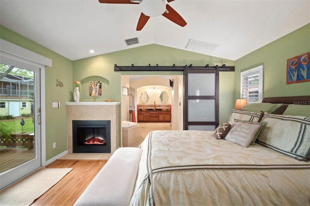 bedroom featuring a barn door, lofted ceiling, visible vents, and access to exterior