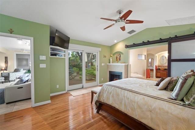 bedroom with visible vents, lofted ceiling, access to exterior, a barn door, and light wood-type flooring