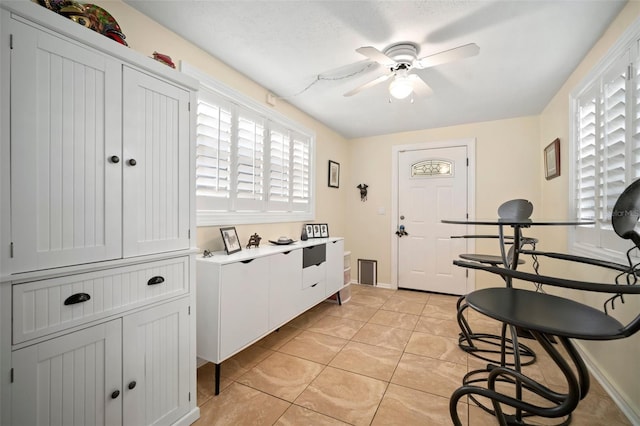 kitchen featuring light tile patterned floors, baseboards, a ceiling fan, and light countertops