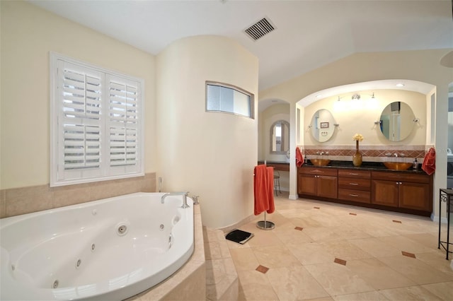 bathroom with visible vents, double vanity, a whirlpool tub, decorative backsplash, and a sink