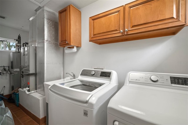 clothes washing area featuring washer and dryer, cabinet space, electric water heater, and dark tile patterned flooring