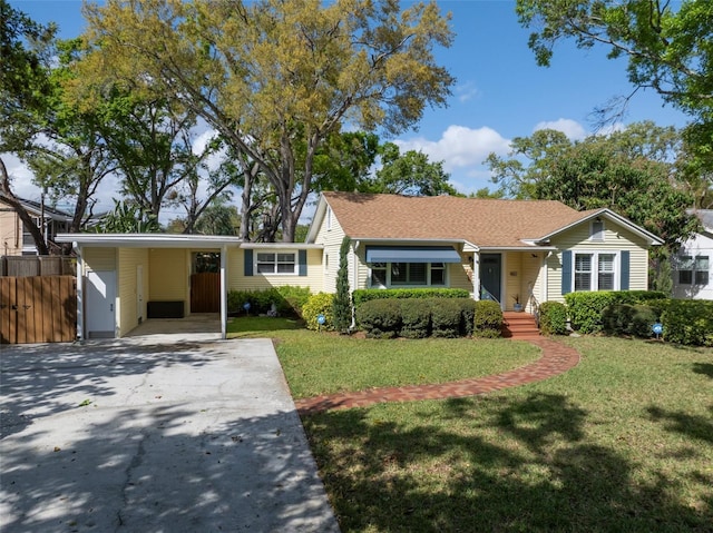 single story home featuring concrete driveway, fence, a front yard, and a carport