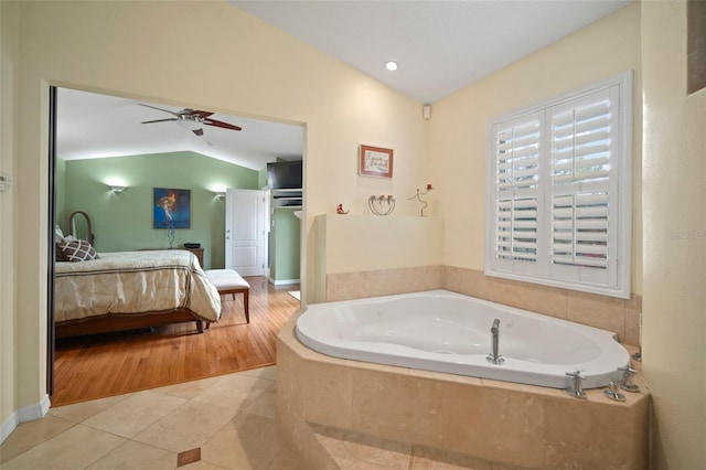 ensuite bathroom with tile patterned flooring, vaulted ceiling, ensuite bathroom, a bath, and a ceiling fan