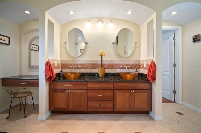 full bath with double vanity, baseboards, tasteful backsplash, and a sink