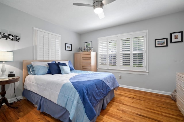 bedroom with a ceiling fan, wood finished floors, and baseboards