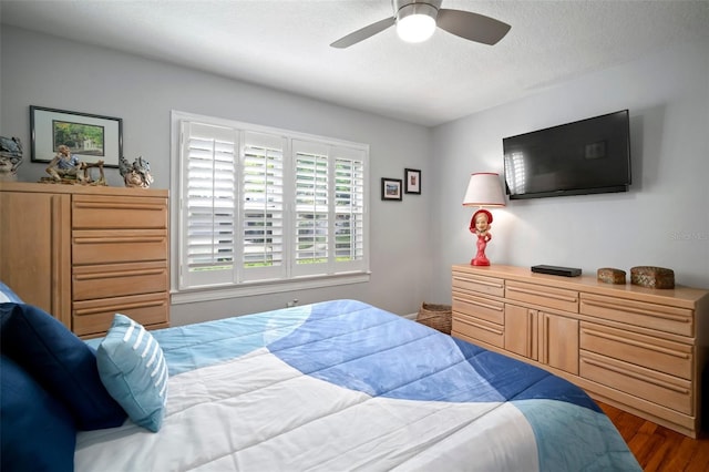 bedroom with a ceiling fan, wood finished floors, and a textured ceiling