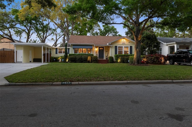 ranch-style home featuring driveway, an attached carport, a front lawn, and fence