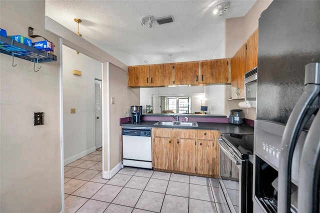 kitchen featuring light tile patterned floors, visible vents, a sink, stainless steel appliances, and dark countertops