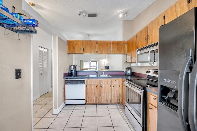 kitchen featuring visible vents, a sink, dark countertops, appliances with stainless steel finishes, and light tile patterned floors