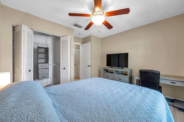 bedroom with a ceiling fan, wood finished floors, visible vents, and a textured ceiling