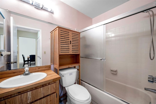 full bath featuring vanity, toilet, and shower / bath combination with glass door