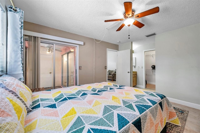 bedroom featuring wood finished floors, baseboards, visible vents, ceiling fan, and a textured ceiling