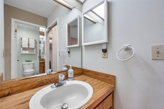 bathroom with toilet, a textured ceiling, and vanity