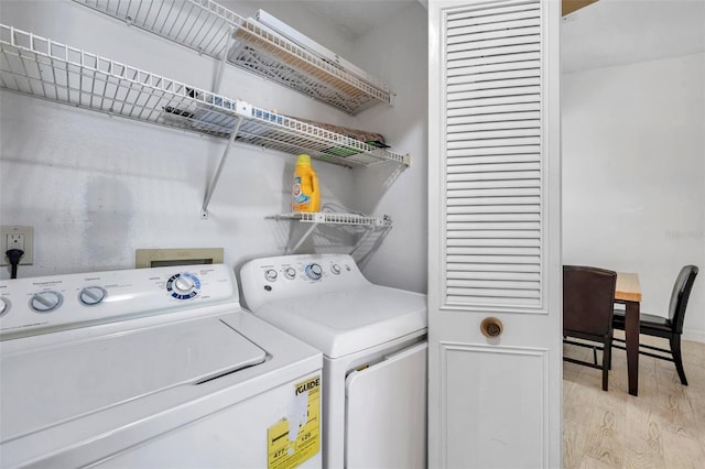 clothes washing area featuring washer and dryer, laundry area, and light wood-style floors