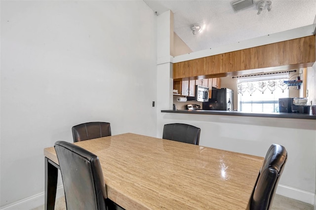 dining room with lofted ceiling, baseboards, visible vents, and a textured ceiling