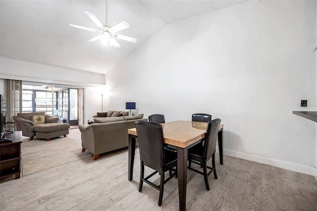 dining room with ceiling fan, baseboards, light wood-style flooring, and vaulted ceiling