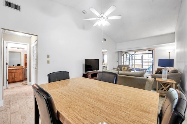 dining space with visible vents, light wood-style floors, ceiling fan, and high vaulted ceiling